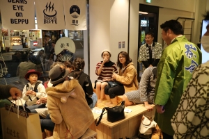 「BEPPU」の暖簾のかかった新宿のビームスの足湯で、緑色の法被を着てお客さんと対面する長野市長の写真